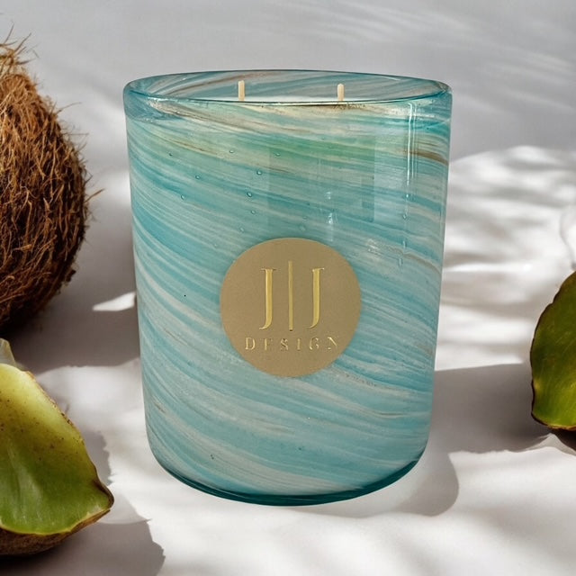 JJ Design 1kg Coconut + Guava Scented Soy Candle surrounded by fresh coconut and guava leaves on white surface