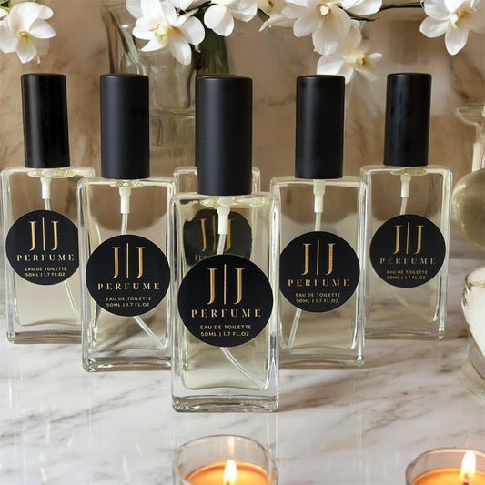 JJ Perfume bottles on a marble surface with flowers in the background