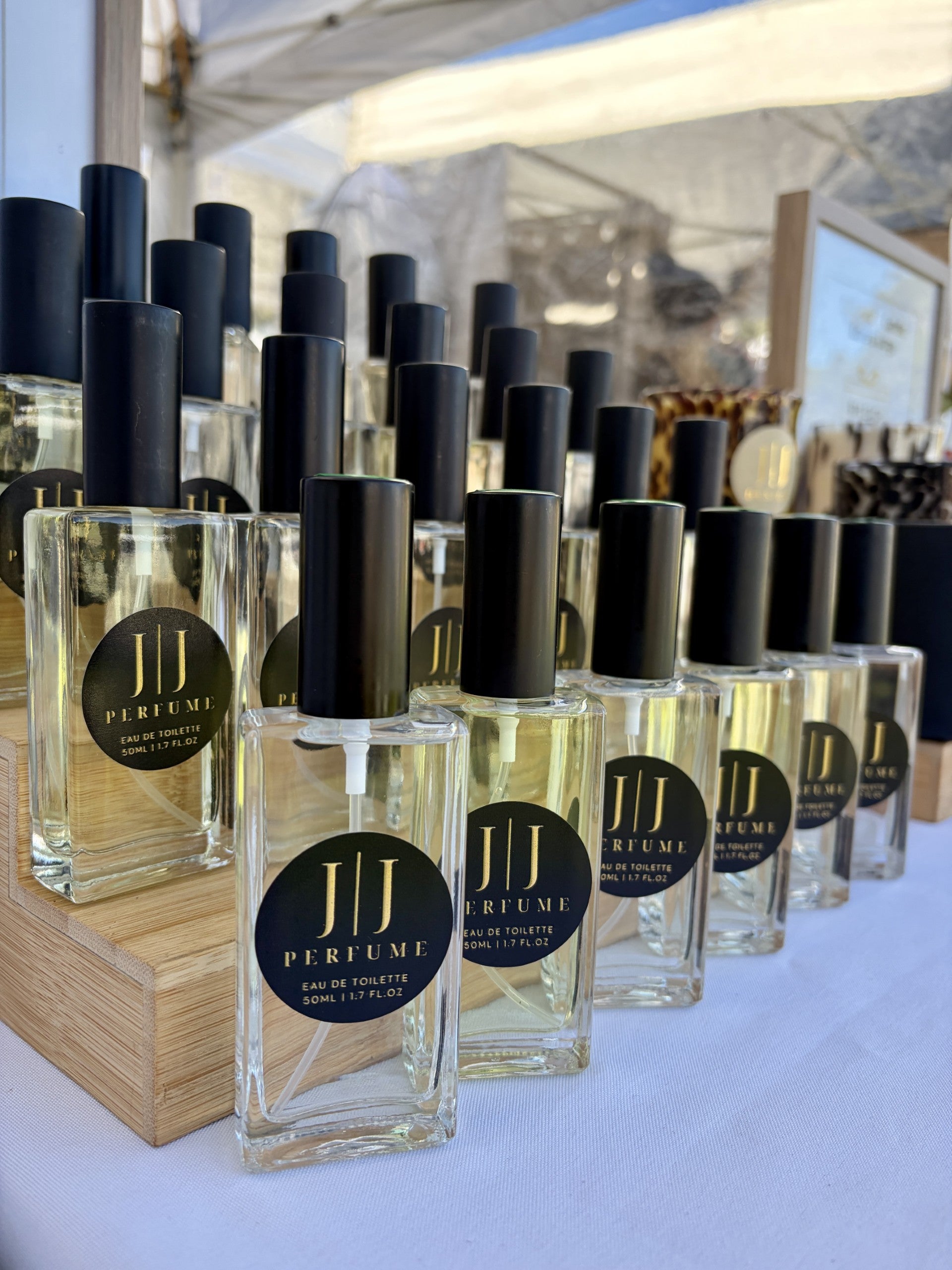 Row of perfume bottles with black caps on a white surface, with a blurred indoor background.