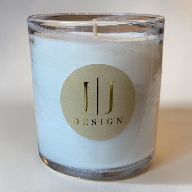 White candle in clear glass jar with gold label.